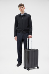 Profile view of model wearing the Oroton Jet Carry On Roller Case in Rich Umber and Durable polycarbonate shell for Women .