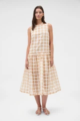 Profile view of model wearing the Oroton Sheer Check Drop Waist Dress in Butterscotch and 80% cotton and 20% lightweight silk blend fabric for Women .