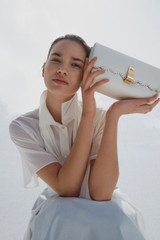 Profile view of model wearing the Oroton Etta Smooth Broidery Medium Clutch in Warm White and Smooth cow leather for Women .