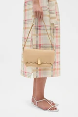 Profile view of model wearing the Oroton Etta Smooth Broidery Medium Clutch in Butterscotch and Smooth cow leather for Women .