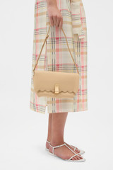 Profile view of model wearing the Oroton Etta Smooth Broidery Medium Clutch in Butterscotch and Smooth cow leather for Women .