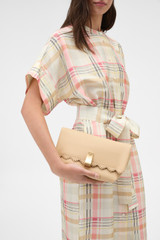 Profile view of model wearing the Oroton Etta Smooth Broidery Medium Clutch in Butterscotch and Smooth cow leather for Women .