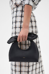Profile view of model wearing the Oroton Myrtle Satin Mini Bag in Black and Satin fabric material for Women .