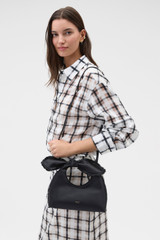 Profile view of model wearing the Oroton Myrtle Satin Mini Bag in Black and Satin fabric material for Women .