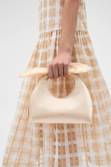 Profile view of model wearing the Oroton Myrtle Satin Mini Bag in Peach and Satin fabric material for Women .