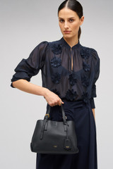 Profile view of model wearing the Oroton Margot Mini Day Bag in Black and Pebble Leather for Women .