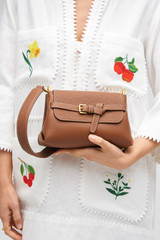 Profile view of model wearing the Oroton Margot Small Top Handle in Whiskey and Premium pebble leather for Women .