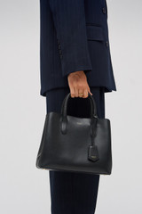 Profile view of model wearing the Oroton Muse Small Three Pocket Day Bag in Black and Saffiano And Smooth Leather for Women .