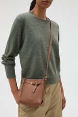 Profile view of model wearing the Oroton Margot Tiny Bucket Bag in Whiskey and Premium smooth leather for Women .