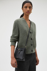 Profile view of model wearing the Oroton Margot Tiny Bucket Bag in Black and Premium pebble leather for Women .