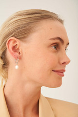 Profile view of model wearing the Oroton Violet Pearl Huggies in Silver/White and Brass Base With Rhodium Plating for Women .