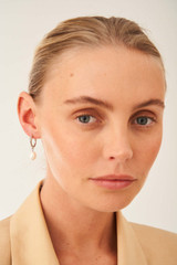Profile view of model wearing the Oroton Violet Pearl Huggies in Silver/White and Brass Base With Rhodium Plating for Women .