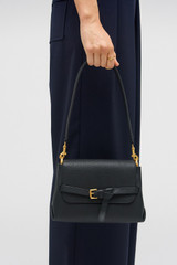 Profile view of model wearing the Oroton Margot Small Top Handle in Black and Premium pebble leather for Women .