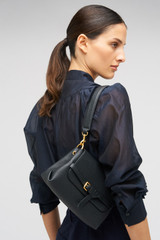Profile view of model wearing the Oroton Margot Small Top Handle in Black and Premium pebble leather for Women .