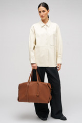 Profile view of model wearing the Oroton Margot Weekender in Whiskey and Pebble Leather for Women .