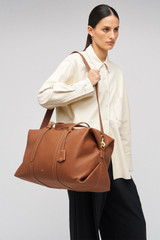 Profile view of model wearing the Oroton Margot Weekender in Whiskey and Pebble Leather for Women .