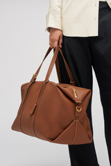 Profile view of model wearing the Oroton Margot Weekender in Whiskey and Pebble Leather for Women .