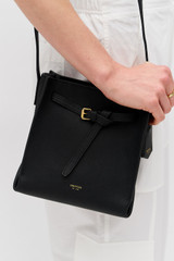 Profile view of model wearing the Oroton Margot Mini Bucket Bag in Black and Pebble leather for Women .