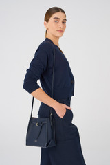 Profile view of model wearing the Oroton Margot Mini Bucket Bag in North Sea and Pebble Leather for Women .