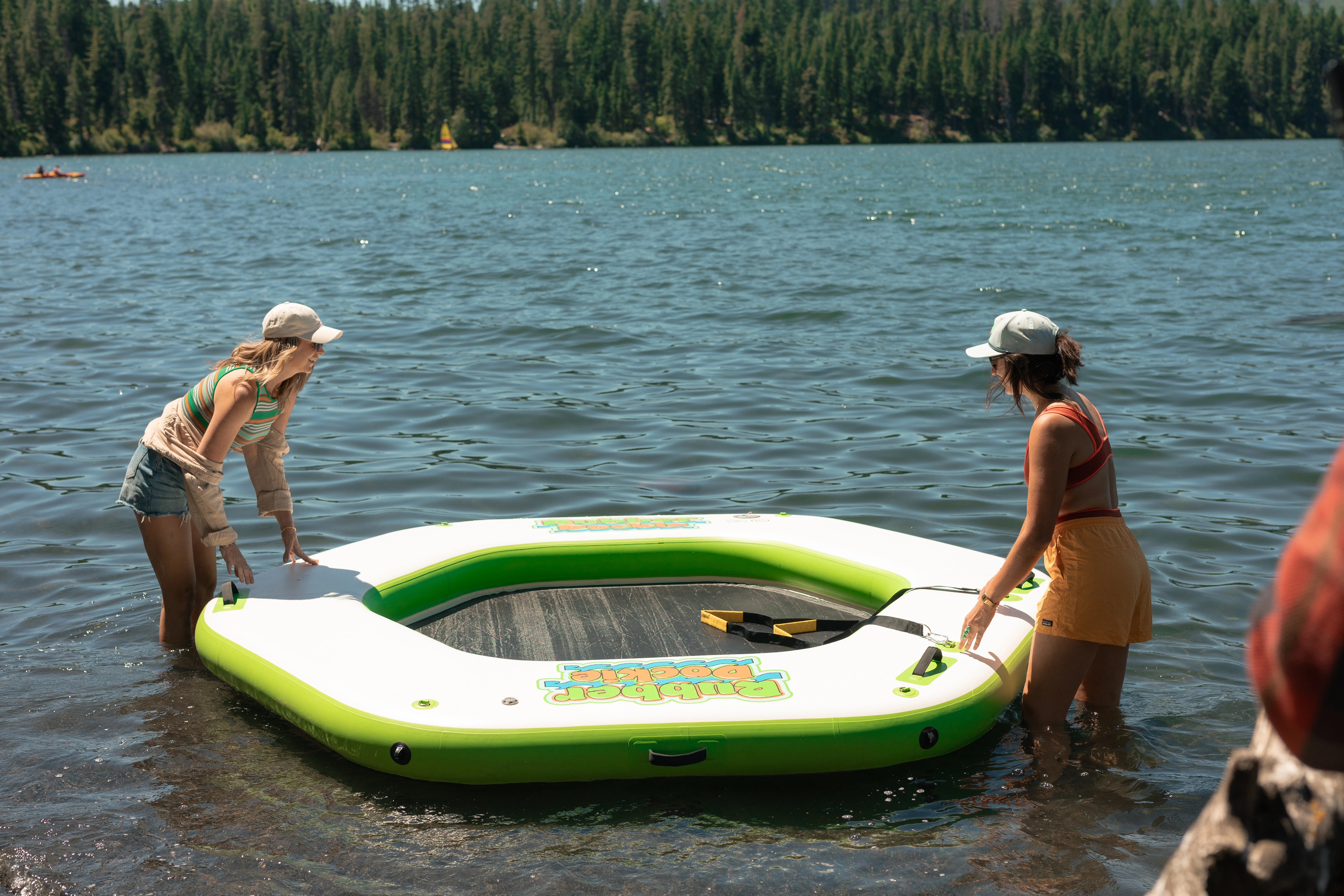 Two people setting up the Rubber Dockie Hex 10 inflatable water hammock on a lake