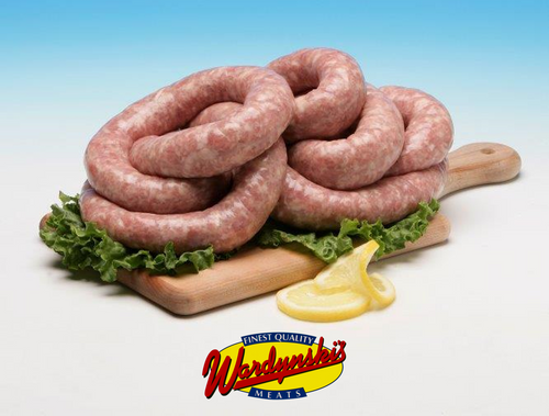 Wardynski fresh Polish sausage coil on wooden cutting board with lemon slices