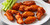 Buffalo style chicken wings coated in classic hot sauce served on a plate with celery sticks.