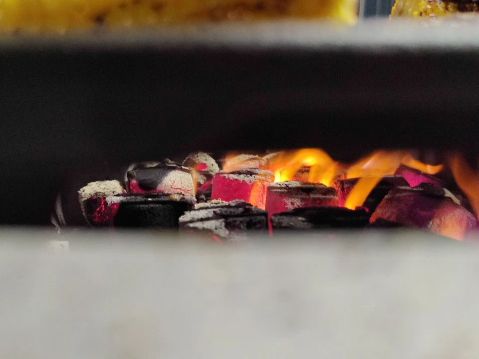 COCO-BBQ coconut shell charcoal glowing red beneath the grill with golden flames