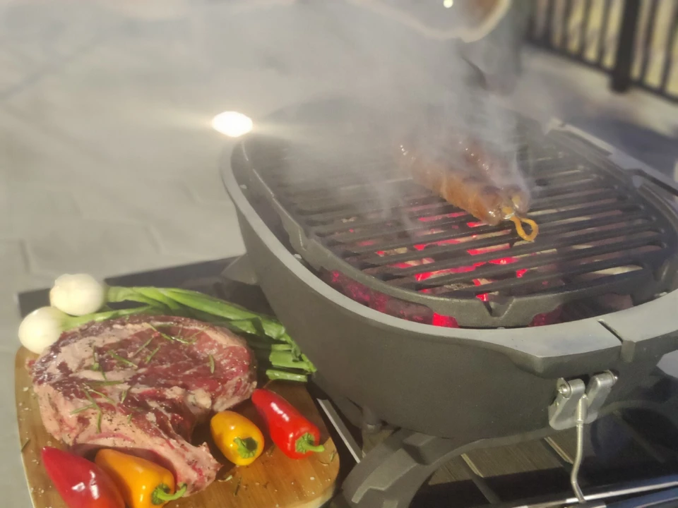 Steak and vegetables prepared beside a glowing charcoal grill