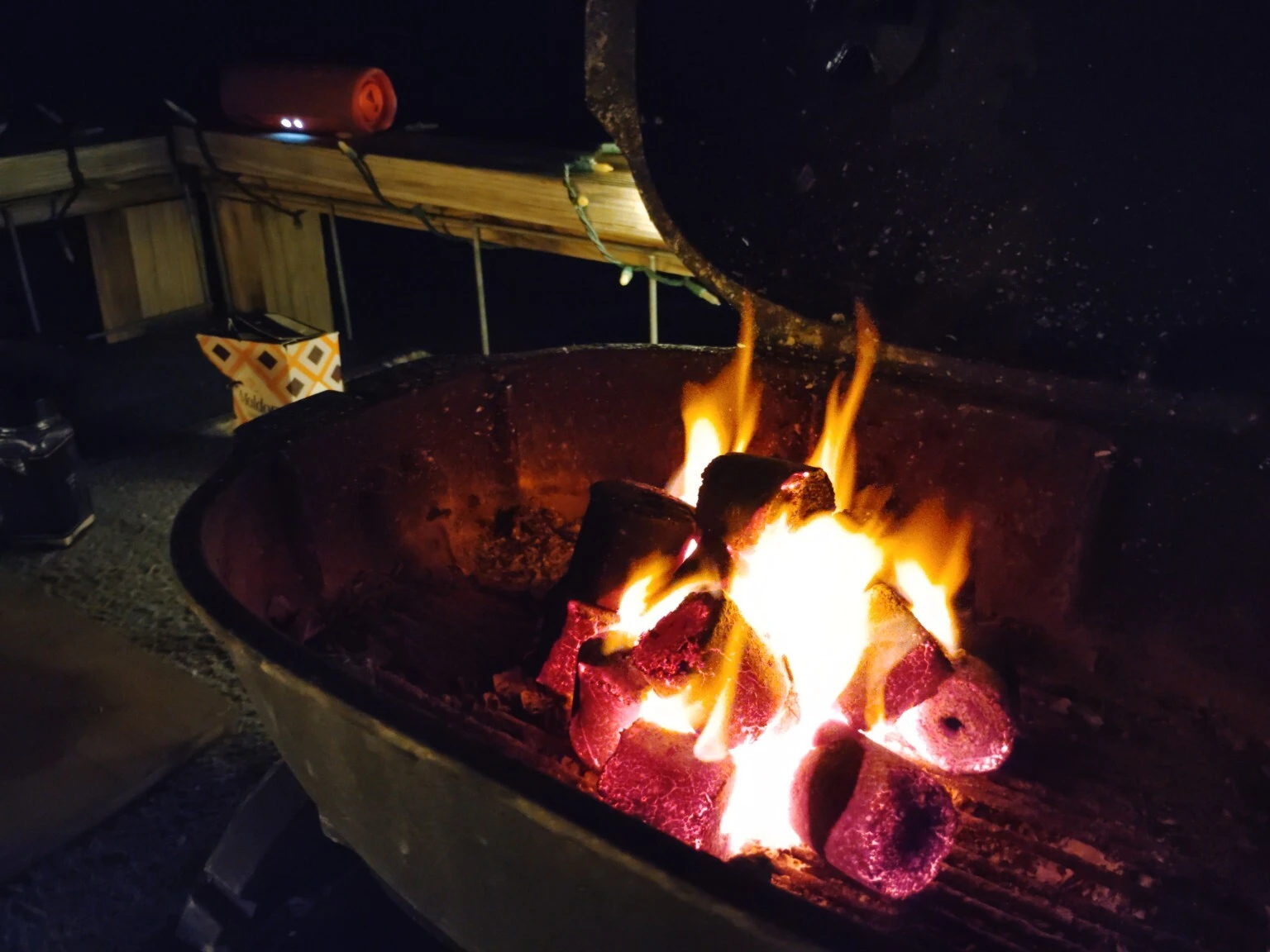 Real COCO-BBQ cylindrical coconut shell charcoal glowing in a backyard grill at night