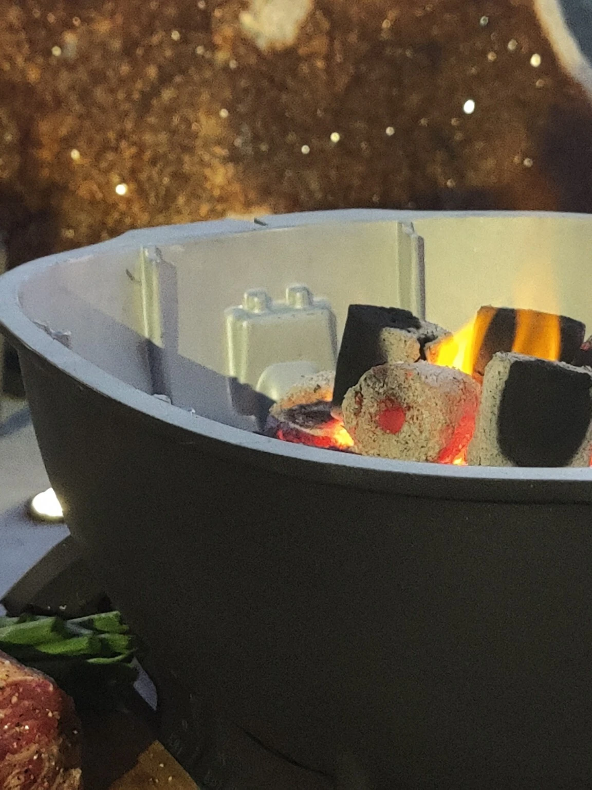 Flames rising from coconut charcoal in a kettle grill