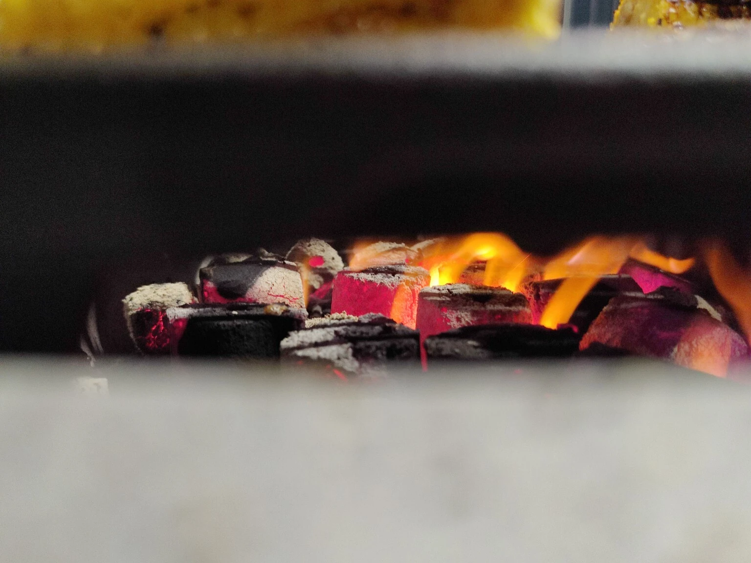 COCO-BBQ coconut shell charcoal glowing red beneath the grill with golden flames