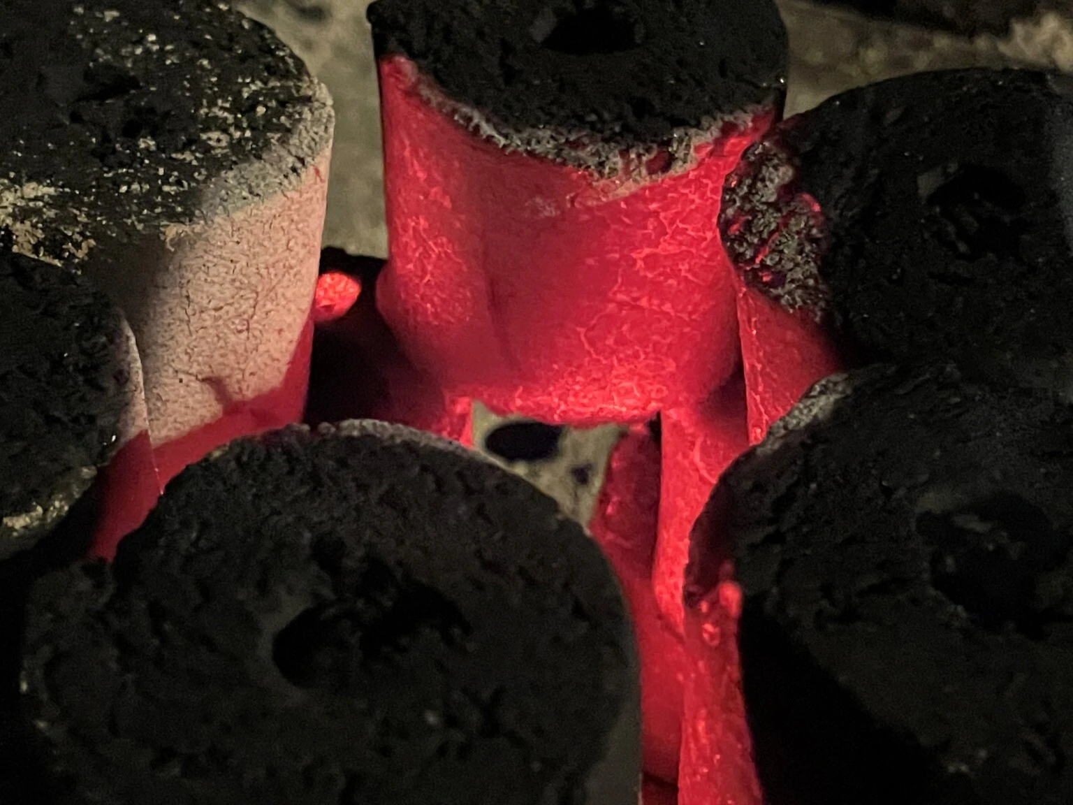 Coconut shell charcoal glowing red with flames in a barbecue grill