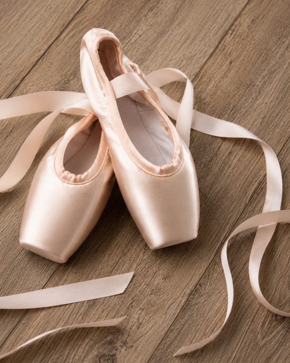 Pair of pink satin pointe shoes with ribbons