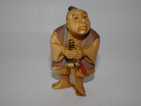 Japanese ivory netsuke of man holding a sword, signed.