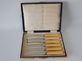 Set of six vintage stainless steel butter knives with cream ivorine-style handles in the original presentation box, dating from the 1930s–1940s.