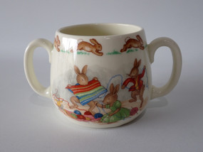 Vintage Royal Doulton Bunnykins two-handled ceramic mug featuring rabbits knitting with colourful wool and hopping rabbits around the rim.