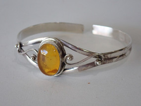 Vintage sterling silver open cuff bangle with oval honey-coloured Baltic amber cabochon and flowing Art Nouveau style silver scrollwork.