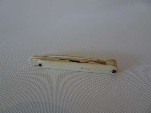 Antique French ivory folding manicure set with concealed nail tools and aged ivory case, measuring approximately 6.5 cm.