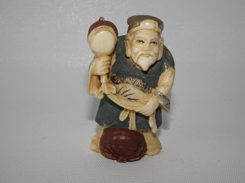 Antique Japanese ivory netsuke of Jurojin holding a tool and scroll, wearing traditional robes, finely carved and signed, 5cm tall.