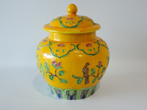 Vintage Chinese yellow ground ginger jar with raised enamel bird and floral decoration, matching lid and wooden stand, 18 cm high.