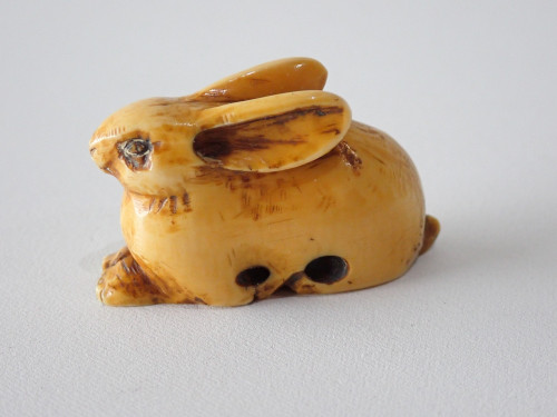 19th-century Japanese ivory rabbit netsuke with folded ears, rich honey patina and historical handling wear.