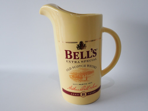 Vintage cream ceramic Bell's Extra Special Scotch Whisky advertising water jug with burgundy lettering and handle, 23cm tall.