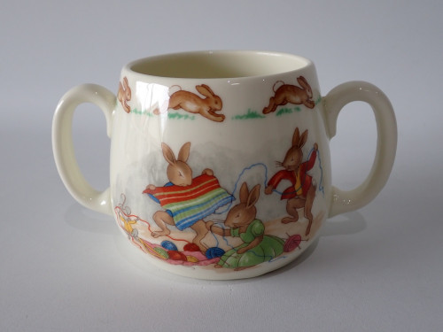 Vintage Royal Doulton Bunnykins two-handled ceramic mug featuring rabbits knitting with colourful wool and hopping rabbits around the rim.
