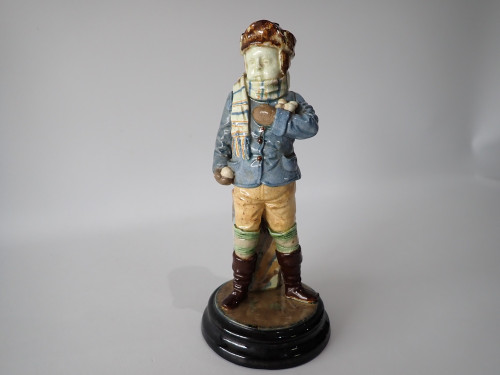 Antique Continental majolica Winter Boy ceramic figurine circa 1890–1910, wearing a blue coat and scarf and holding snowballs beside a stone wall.