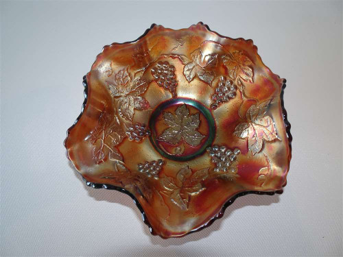 Vintage Fenton purple iridescent carnival glass bowl with embossed grape and vine decoration and ruffled scalloped rim.