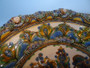 A rare large and heavy Gouda Majolica pottery bowl decorated with flowers in vases to centre and foliage pattern border with faces in relief to rim