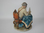 Vintage Italian Pucci porcelain The Stamp Collector figurine depicting a seated gentleman examining stamps beside a lamp and ornate table.