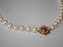 Vintage cultured pearl necklace and bracelet with 14 carat gold clasp set with a central ruby and diamonds displayed on a light background.