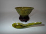 Vintage Chinese spinach jade bowl and matching carved spoon in translucent olive-green stone, displayed on a decorative wooden stand.