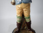 Antique Continental majolica Winter Boy ceramic figurine circa 1890–1910, wearing a blue coat and scarf and holding snowballs beside a stone wall.